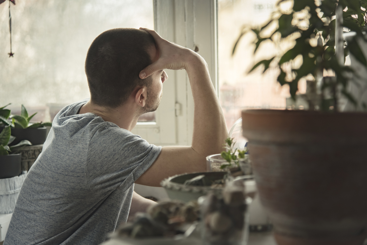 young man feeling loneliness looking out window