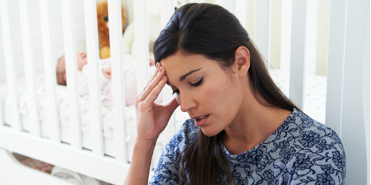 mother with postpartum depression sits by crib