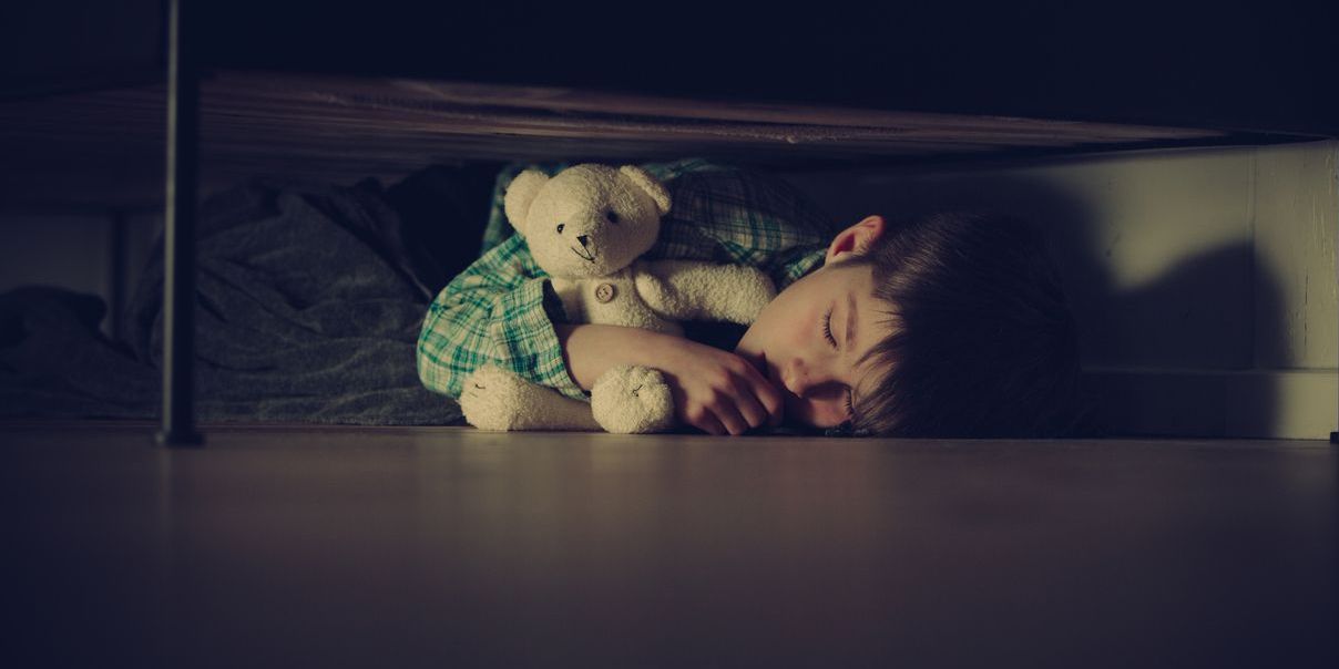 child under bed representing childhood trauma link to mental health