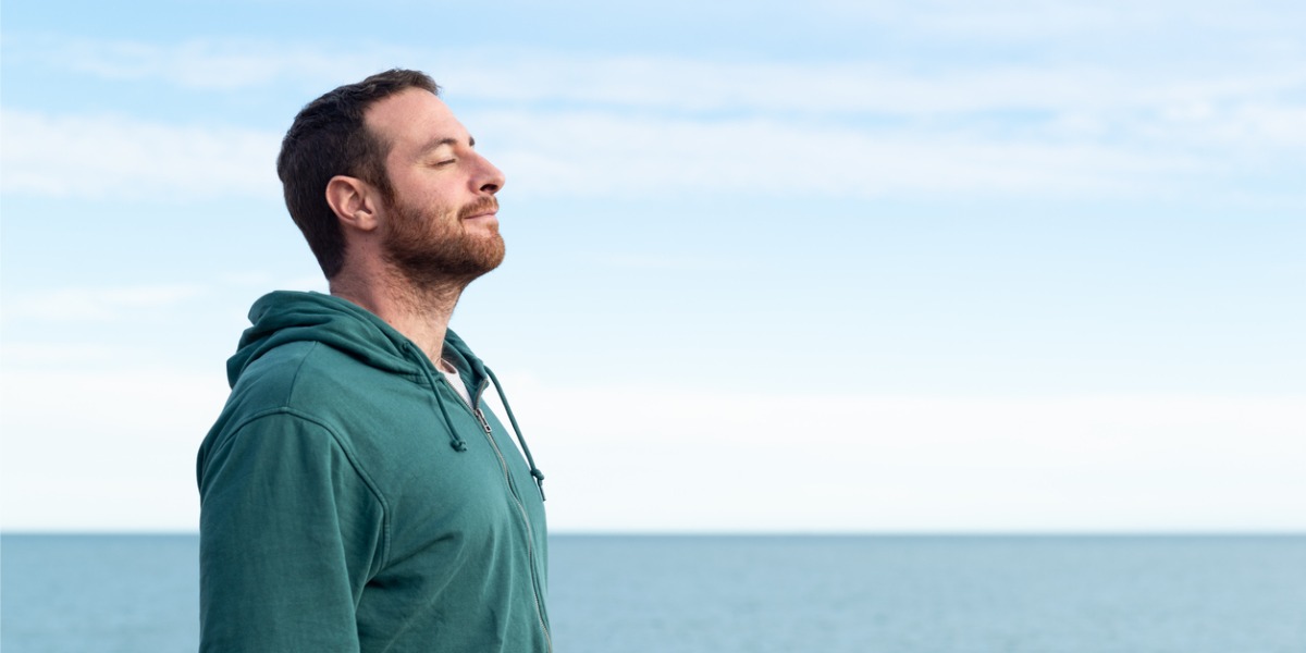 man practicing mindfulness by the ocean