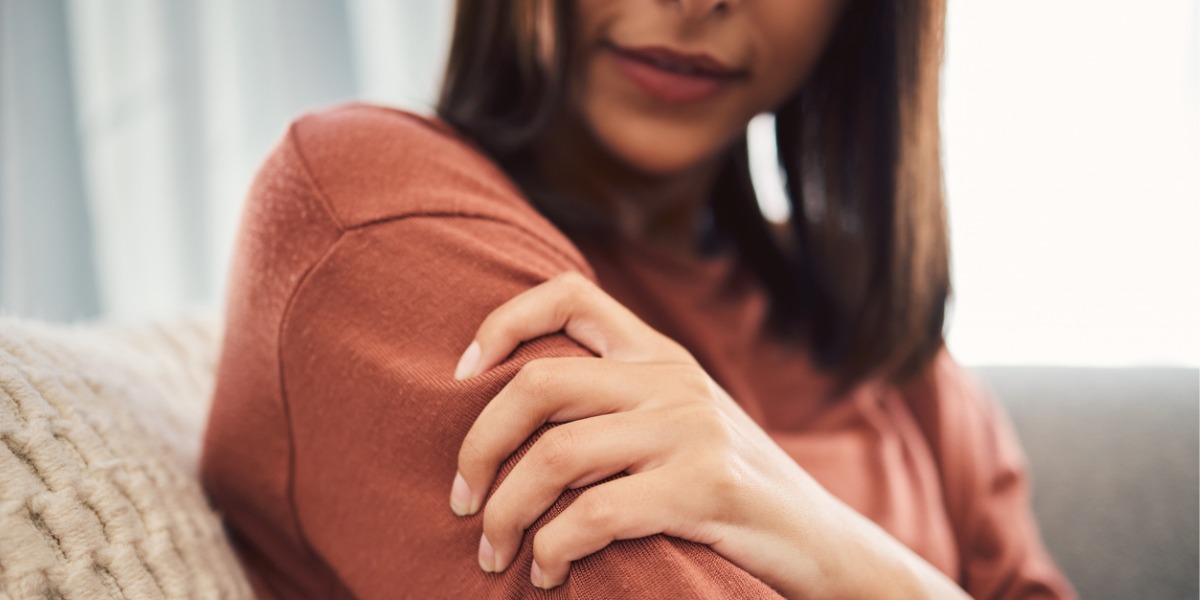 young woman holding arm as sign of heart attack