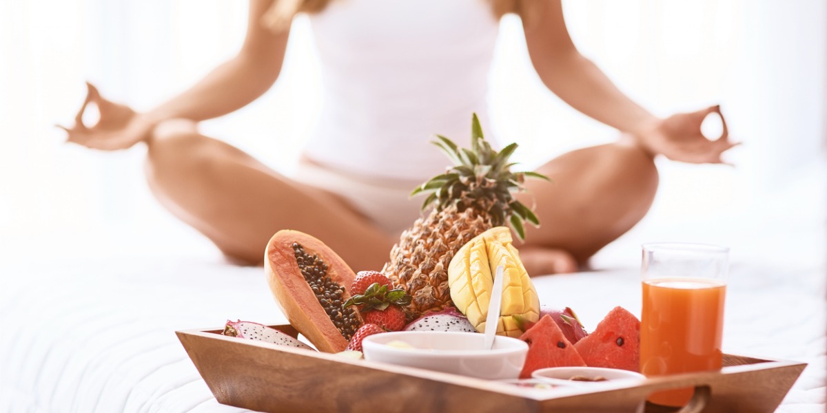 woman meditation next to a bowl of healthy fruits