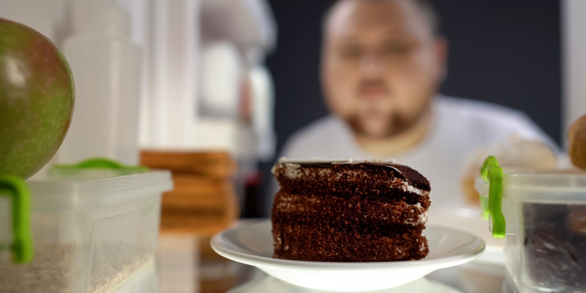 man opening fridge to eye chocolate cake