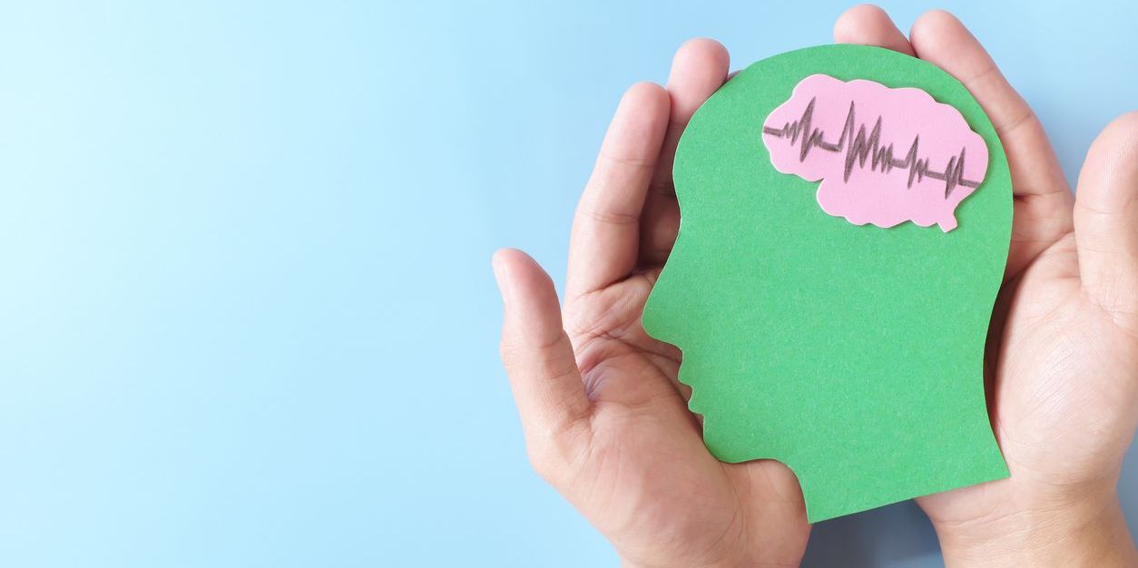hands holding paper cutout of head to illustrate mental health